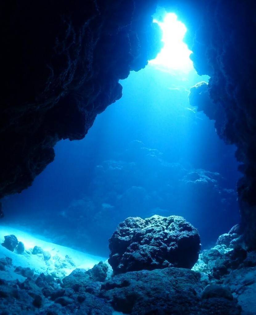糸満沖のクレバスから差し込む青い光を見上げる水中風景